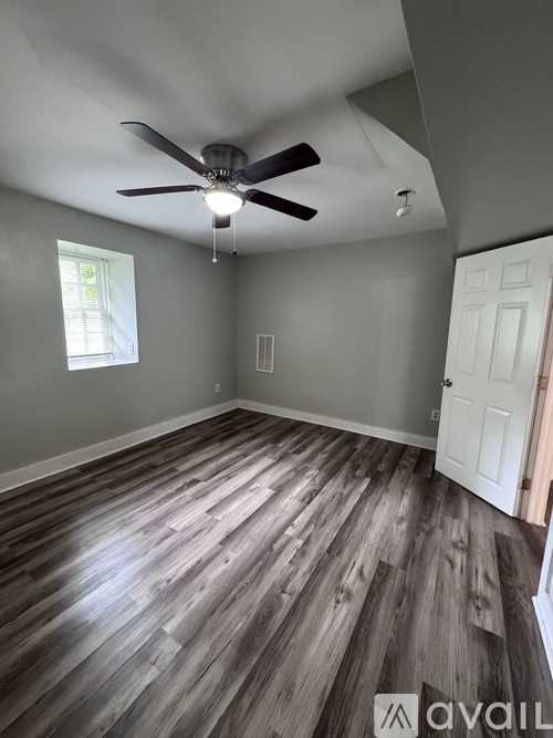 A room with a ceiling fan and wooden flooring.