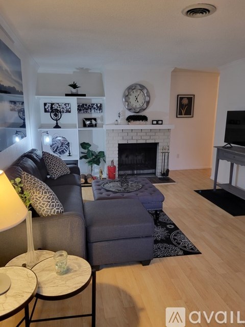 A living room with a grey couch, a fireplace, and a painting on the wall.