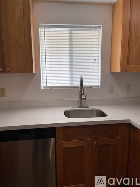 A kitchen with wooden cabinets and a stainless steel dishwasher.