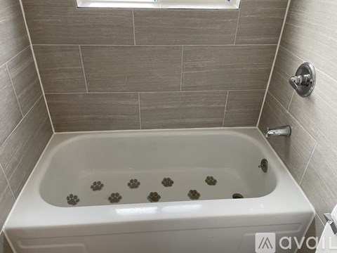 A white bathtub with a faucet and a window in a tiled bathroom.