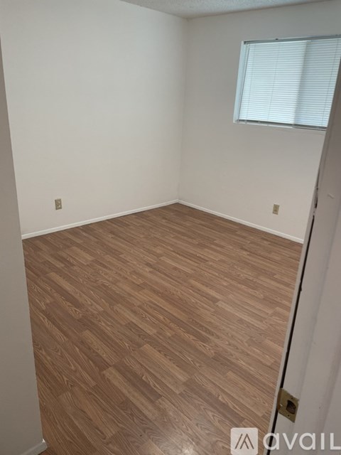 A room with wooden flooring and a window with blinds.