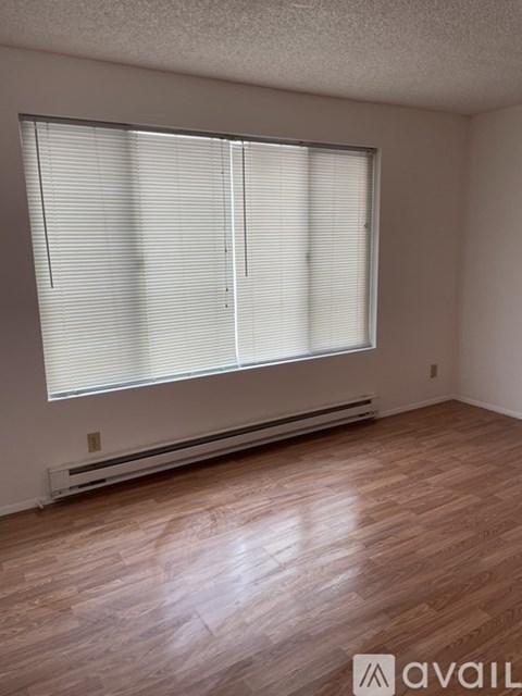 A room with wooden flooring and a window with blinds.