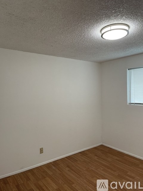 A room with wooden flooring and a window with blinds.