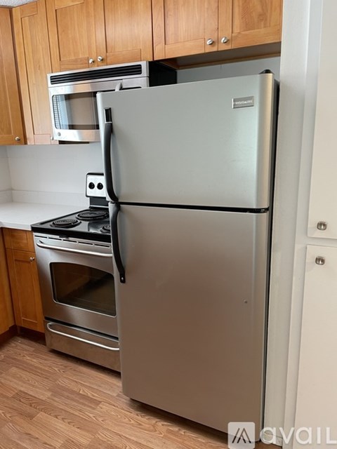 A silver refrigerator stands in a kitchen with wooden cabinets.