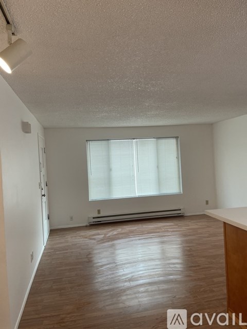 A room with wooden flooring and a window with blinds.