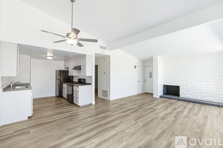 A spacious living room with a fireplace and a kitchen area in the background.