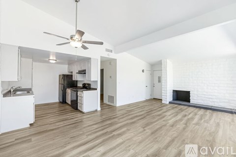 A spacious living room with a fireplace and a kitchen area in the background.