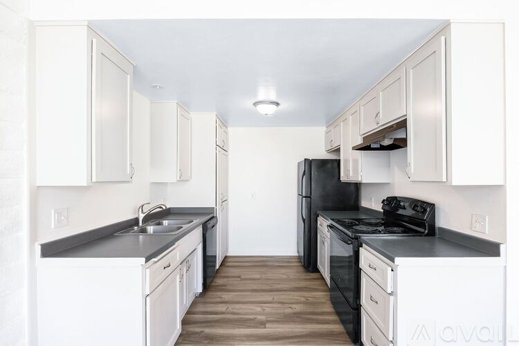 A kitchen with black appliances and white cabinets.
