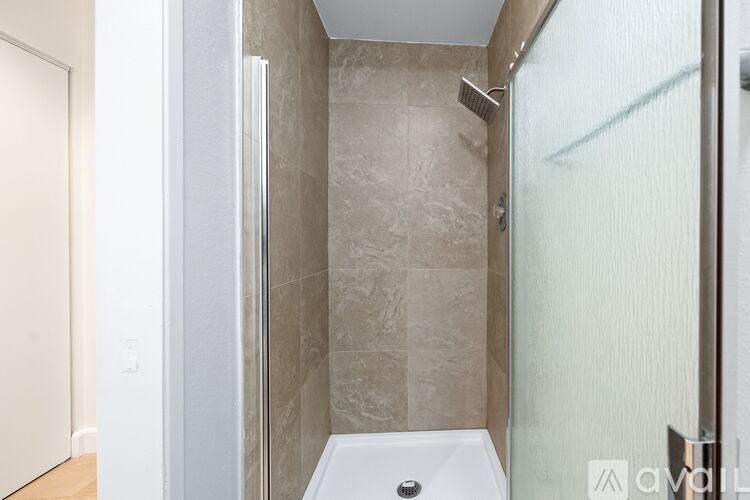 A modern bathroom with a glass shower door and a white bathtub.