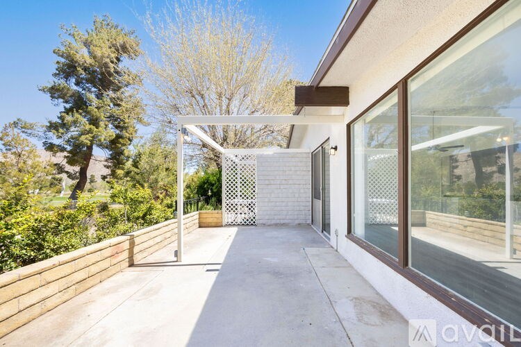 A modern house with a glass wall and a wooden deck.