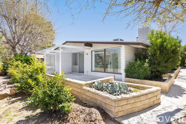 A house with a white exterior and a garden in front.