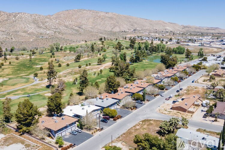 A bird's eye view of a residential area with houses, roads, and a golf course.