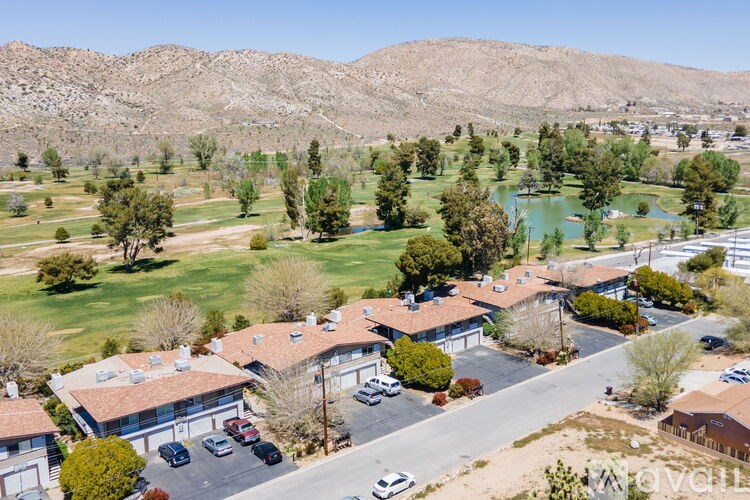 A bird's eye view of a residential area with houses, cars, and a pond.