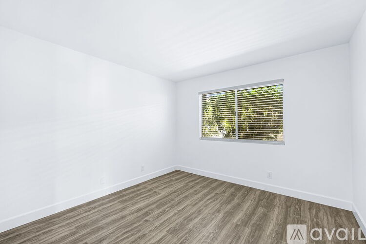 A room with wooden flooring and a window with blinds.