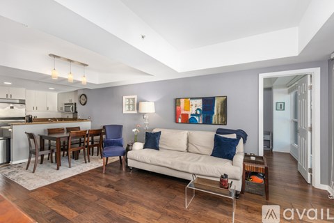 A living room with a white couch and a painting on the wall.