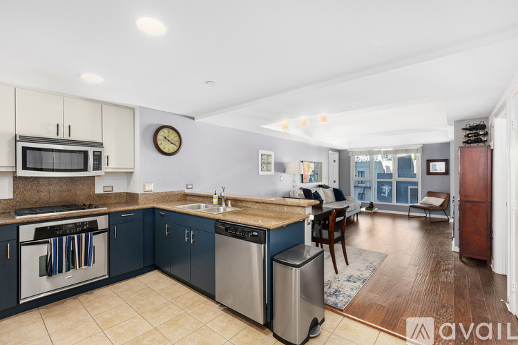 A kitchen with a clock on the wall and a dining table with chairs.