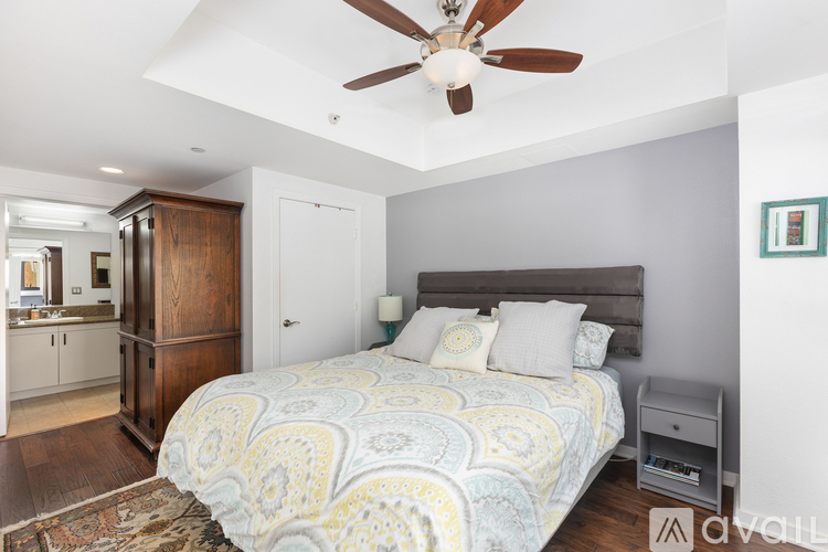 A bedroom with a patterned bedspread and a ceiling fan.