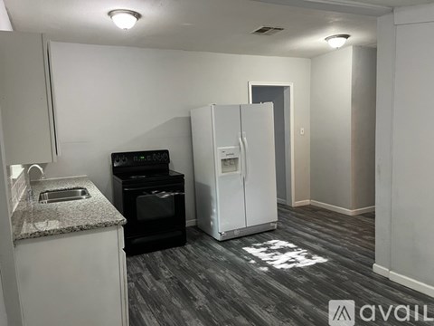 A kitchen area with a black oven, sink, and refrigerator.