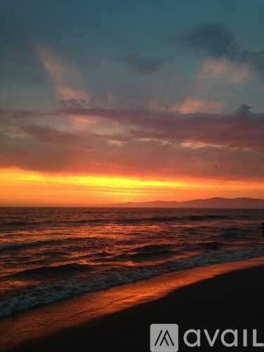A beach at sunset with waves coming in.