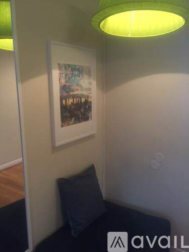 A picture is hanging on the wall above a black couch.