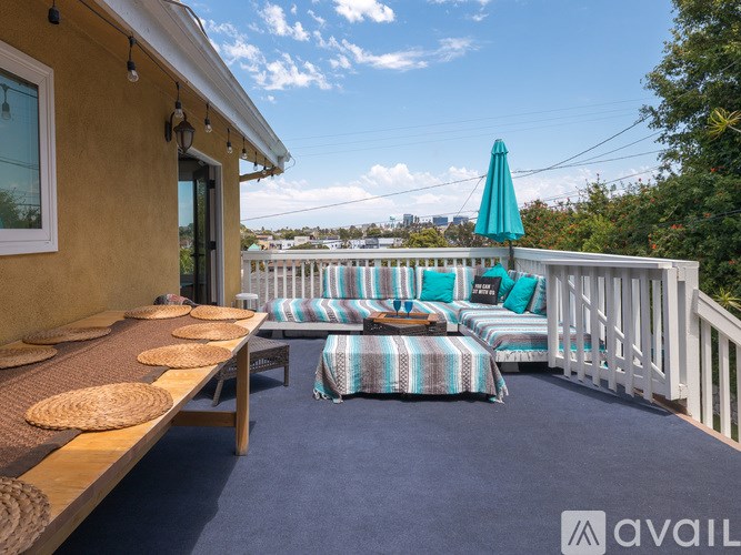 A balcony with a blue cushioned seating area and a green umbrella.