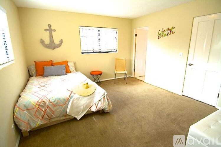 A bedroom with a bed, a chair, and an anchor on the wall.