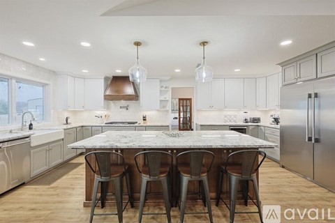 A kitchen with a marble table and stainless steel appliances.