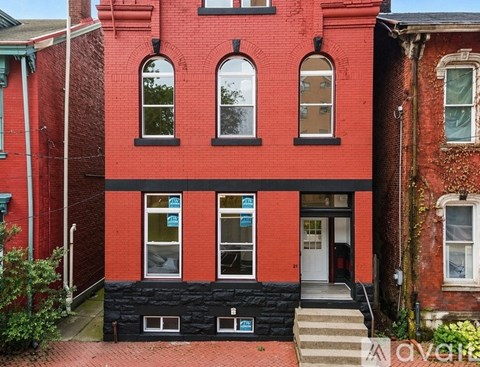 A red brick house with a black roof and a white door.