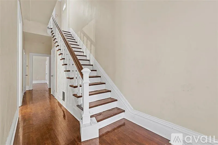 A wooden staircase with white railings leads up to a door.