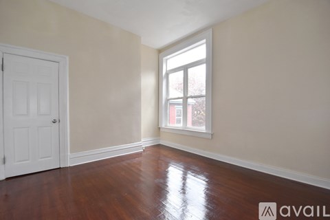 A room with a white door and a window with a view of a red building outside.