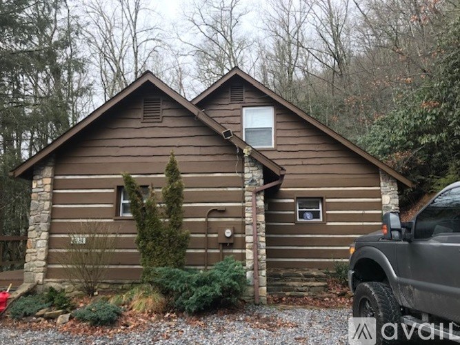 A brown wooden house with a car parked in front.
