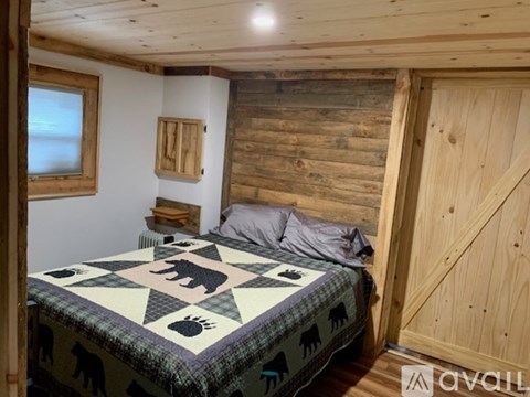 A bedroom with a bed covered in a bear print comforter.