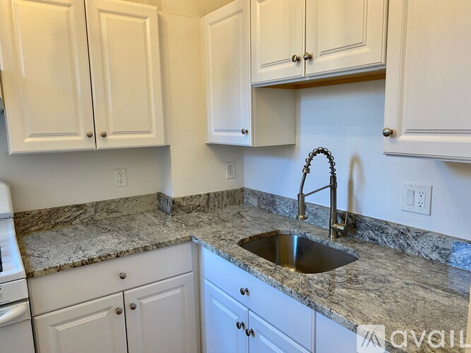 A kitchen with a granite countertop and white cabinets.