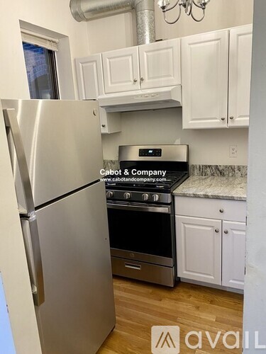 A kitchen with a stainless steel refrigerator and white cabinets.