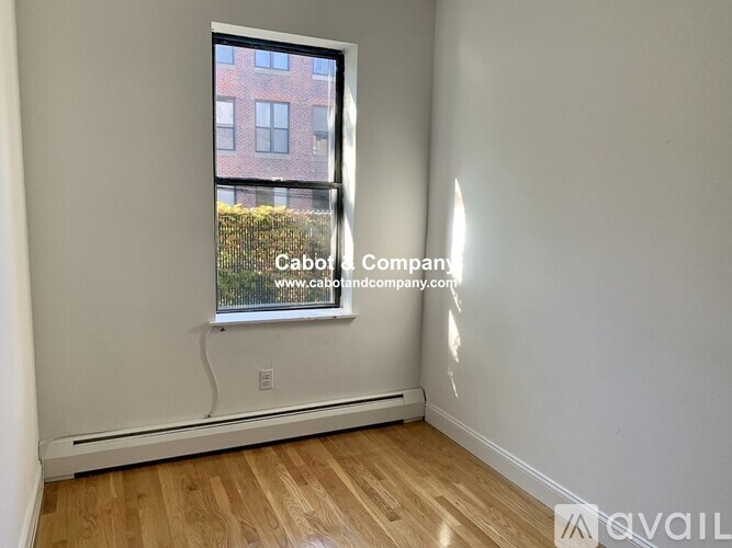 A room with a window showing a building outside.