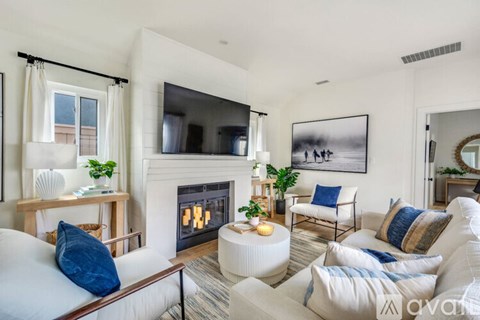 A living room with a fireplace and a television on the wall.