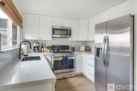 A modern kitchen with white cabinets and stainless steel appliances.