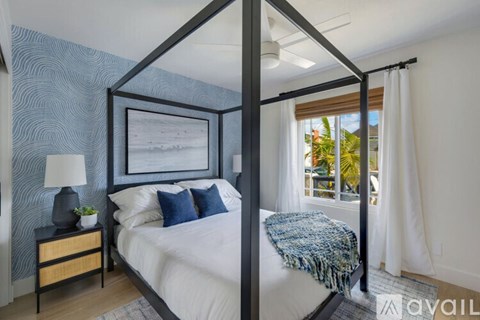 A bedroom with a four poster bed and a window with a view of the outside.