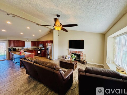 A living room with a brown couch and a ceiling fan.