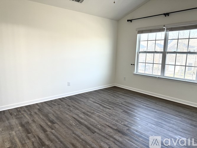A room with a window and wooden flooring is available for rent.