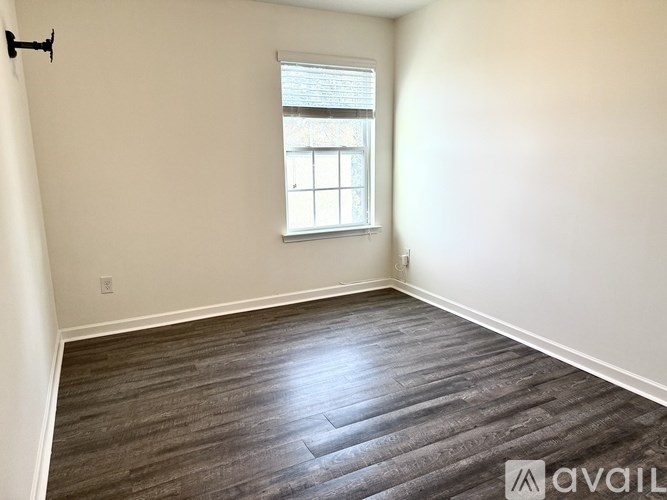 A room with a window and wooden flooring is available for rent.