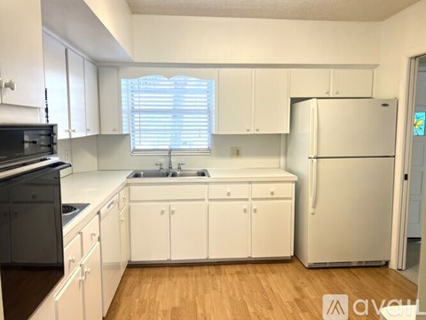 A kitchen with white cabinets and a wooden floor.