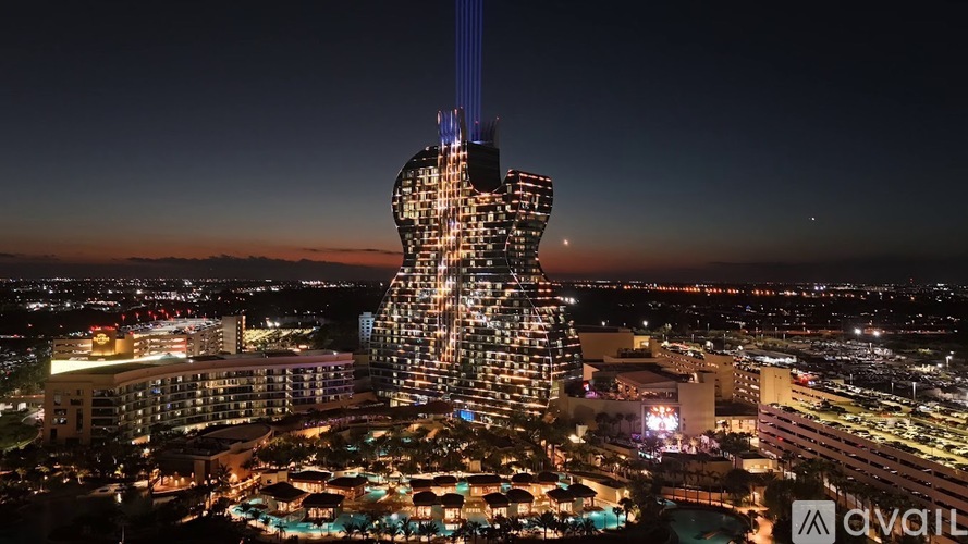 A tall, illuminated building with a unique design stands out against the night sky.