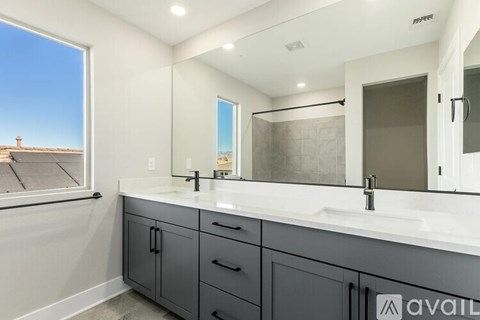 A bathroom with a large mirror, sink, and cabinets.