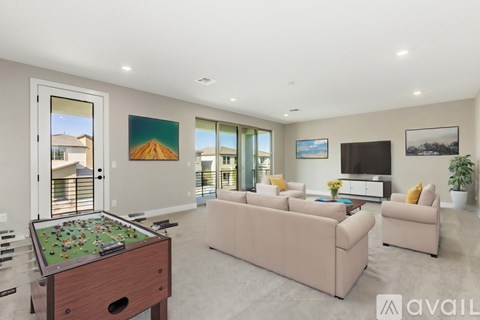 A well-lit living room with a pool table and a couch.