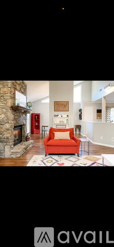 A living room with a red chair and a fireplace.