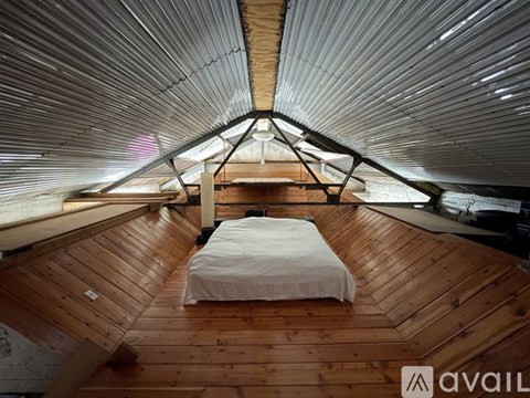 A bedroom with a bed and a wooden floor.