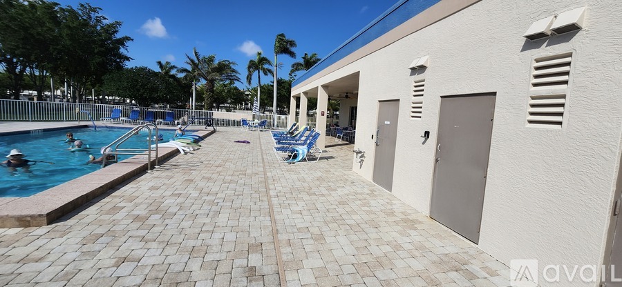 A pool area with people swimming and sun loungers.
