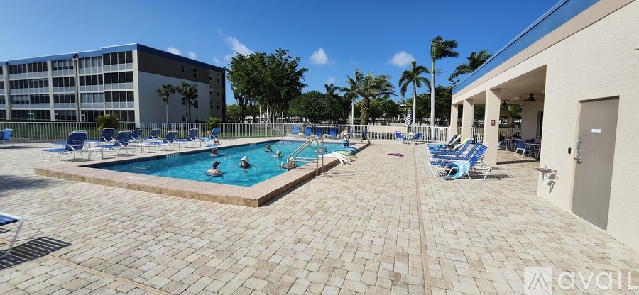 A pool area with a large swimming pool and sun loungers.