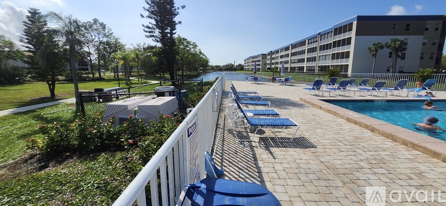 A pool area with blue chairs and a white fence.